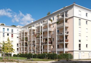 Blick auf ein Mehrfamilienhaus, teils eingezäunt.
